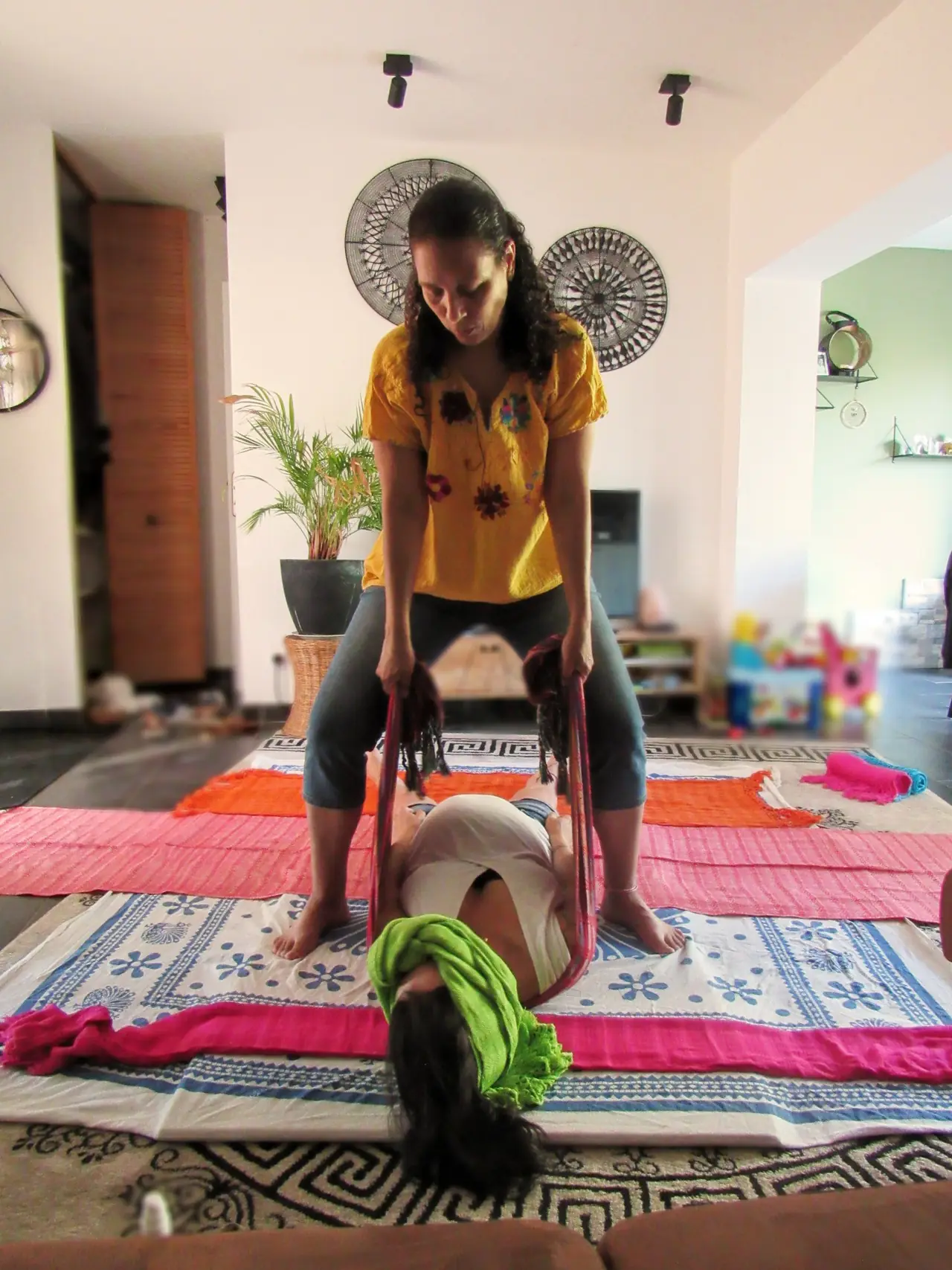 Praticienne berçant avec un rebozo une femme allongée, lors d'une séance de relaxation à domicile
